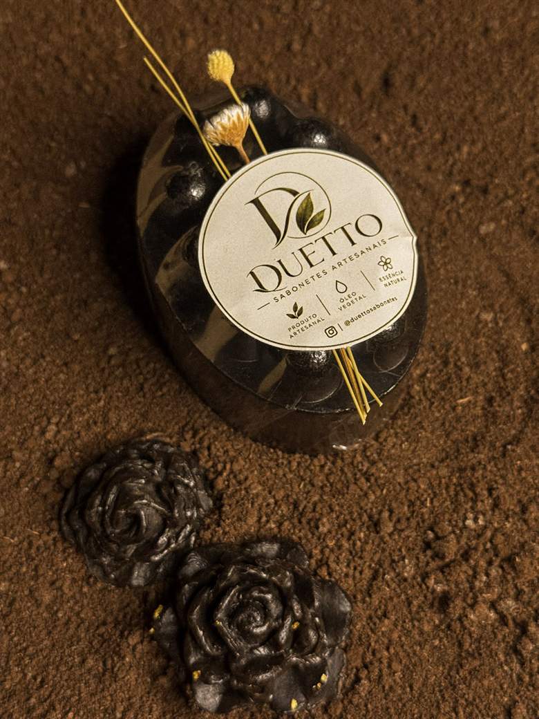 Sabonete massageador preto com rosas de sabonete sobre pó de café