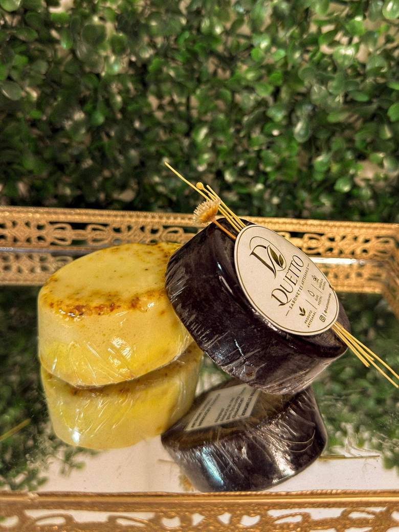 Sabonete oval amarelo e sabonete redondo escuro sobre bandeja espelhada dourada