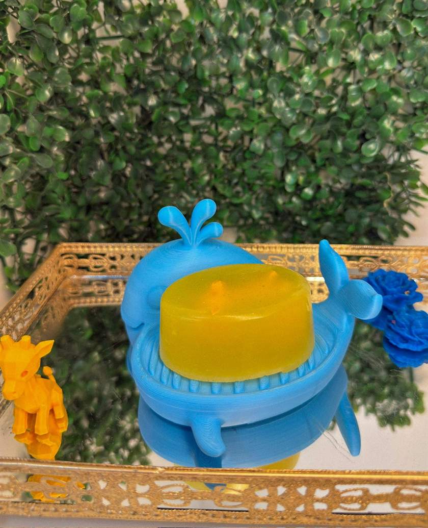Sabonete amarelo com uma girafinha em 3D dentro, segurado por uma mão de luva preta (foto 2 de 3)